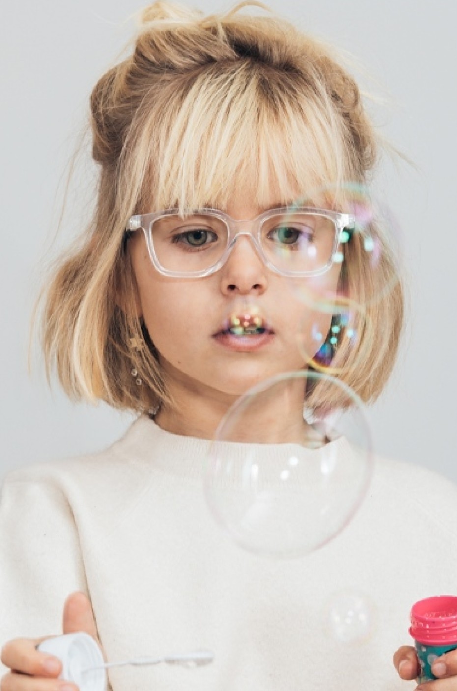 Glorify: Mädchen, das eine Brille trägt und mit Seifenblasen spielt